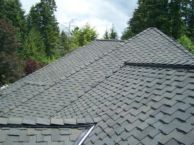 A close-up view of a residential roof covered with gray asphalt shingles