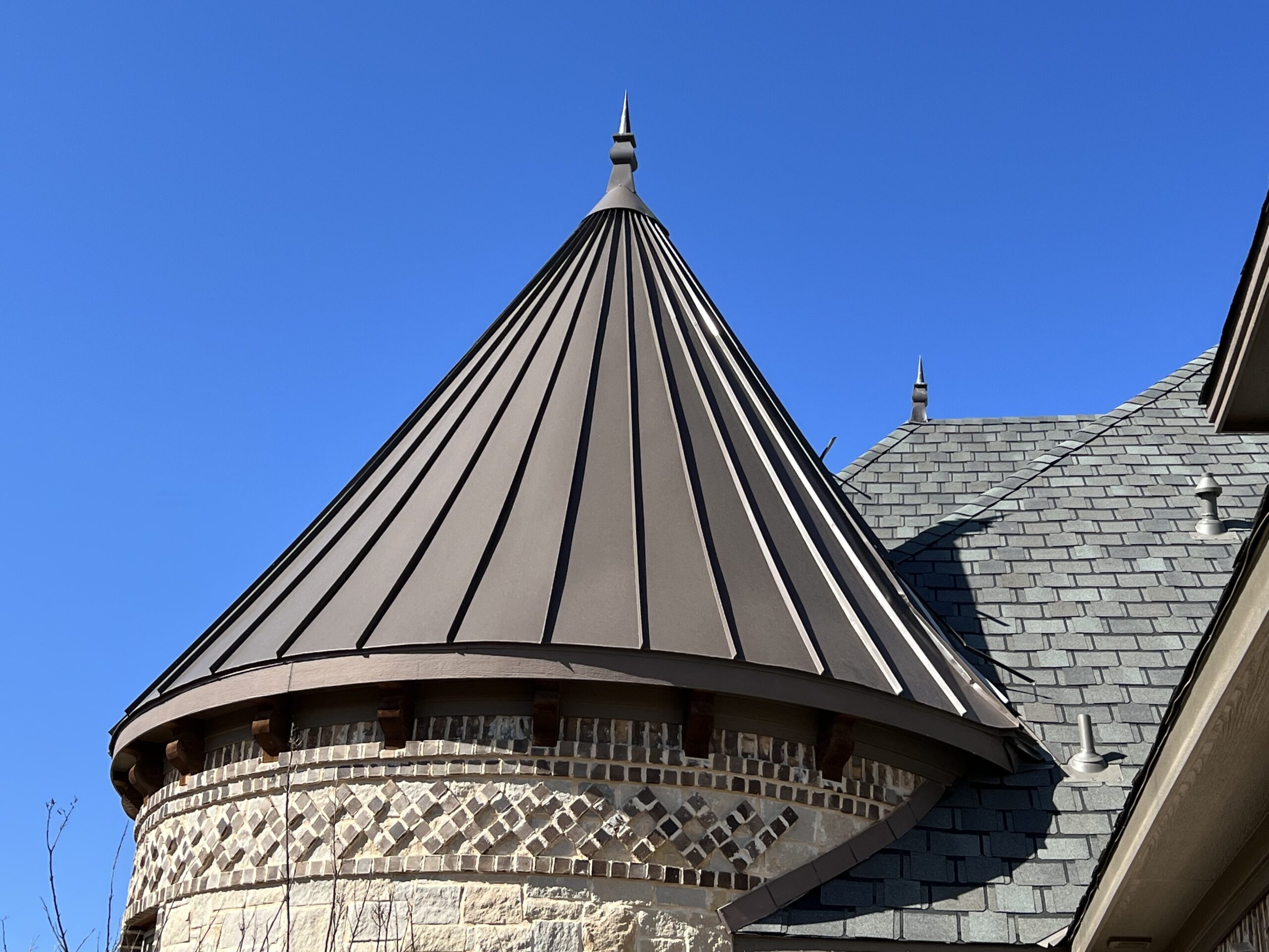A conical roof with a pointed finial on top, made of metal panels
