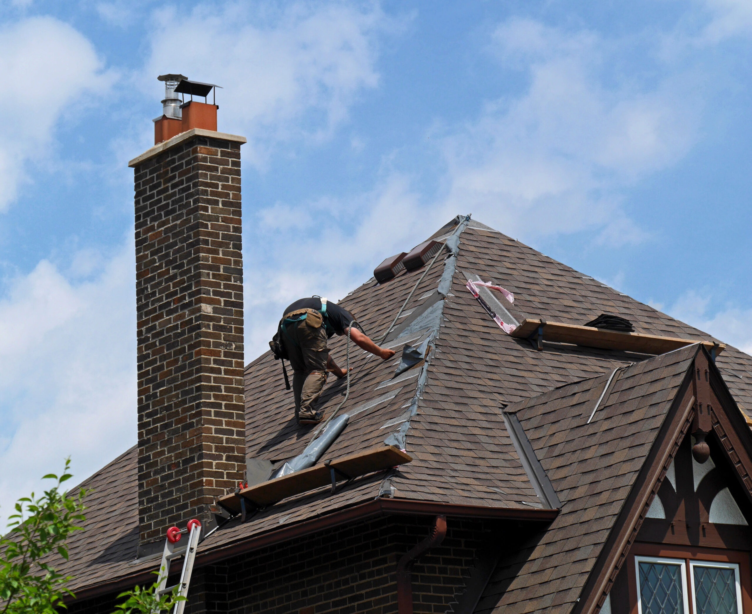 roofer at work repairing a steeply sloped shingle roof